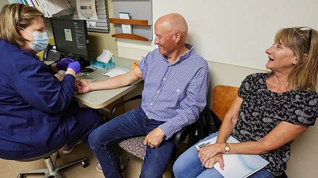 healthcare provider and patient with spouse in examination room