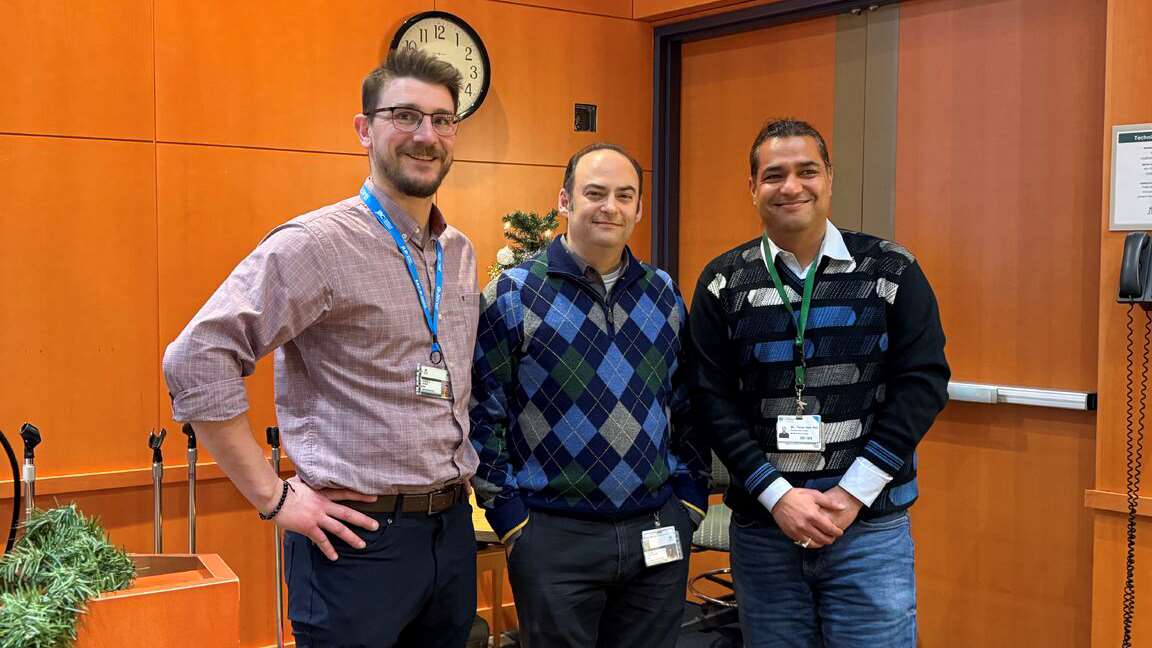 Three men standing in a conference room