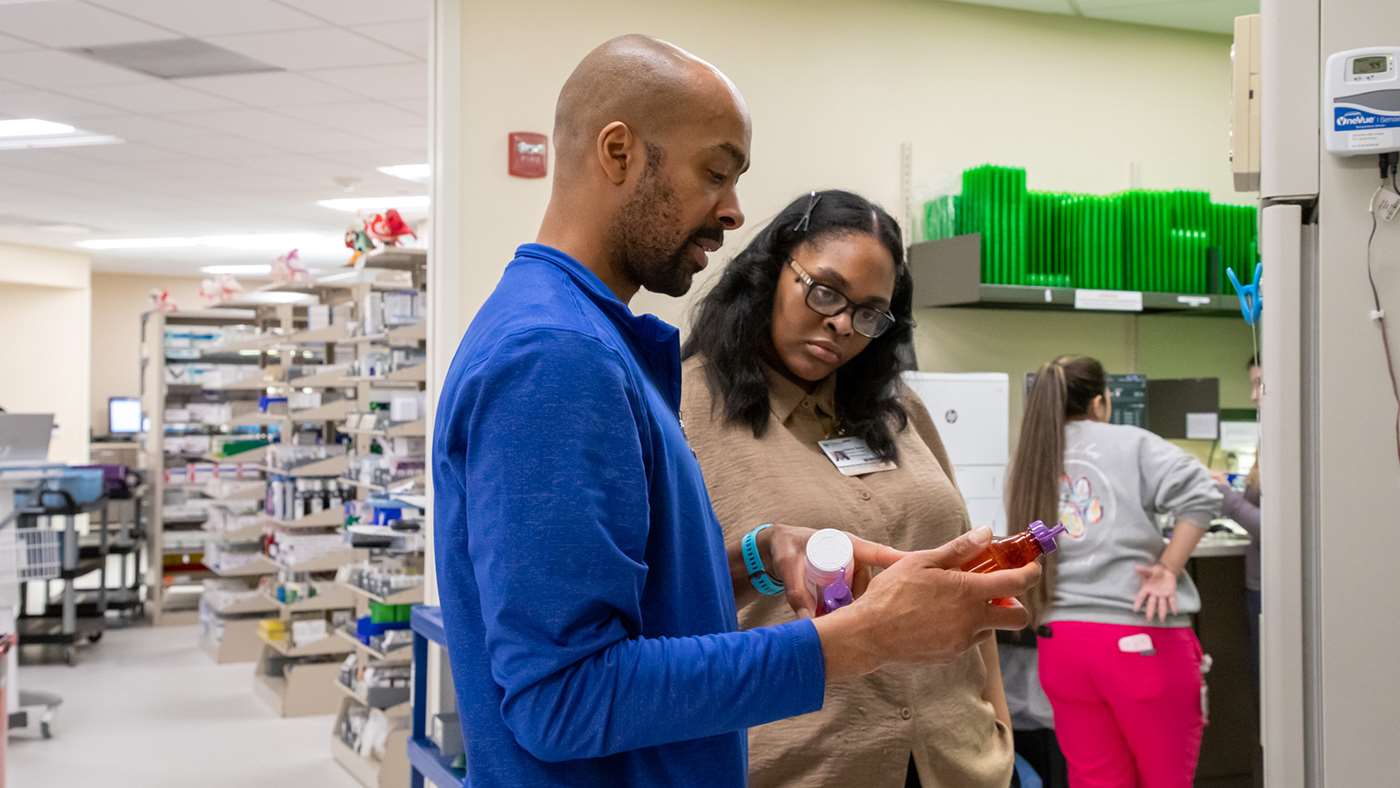 Two people standing and discussing two medications