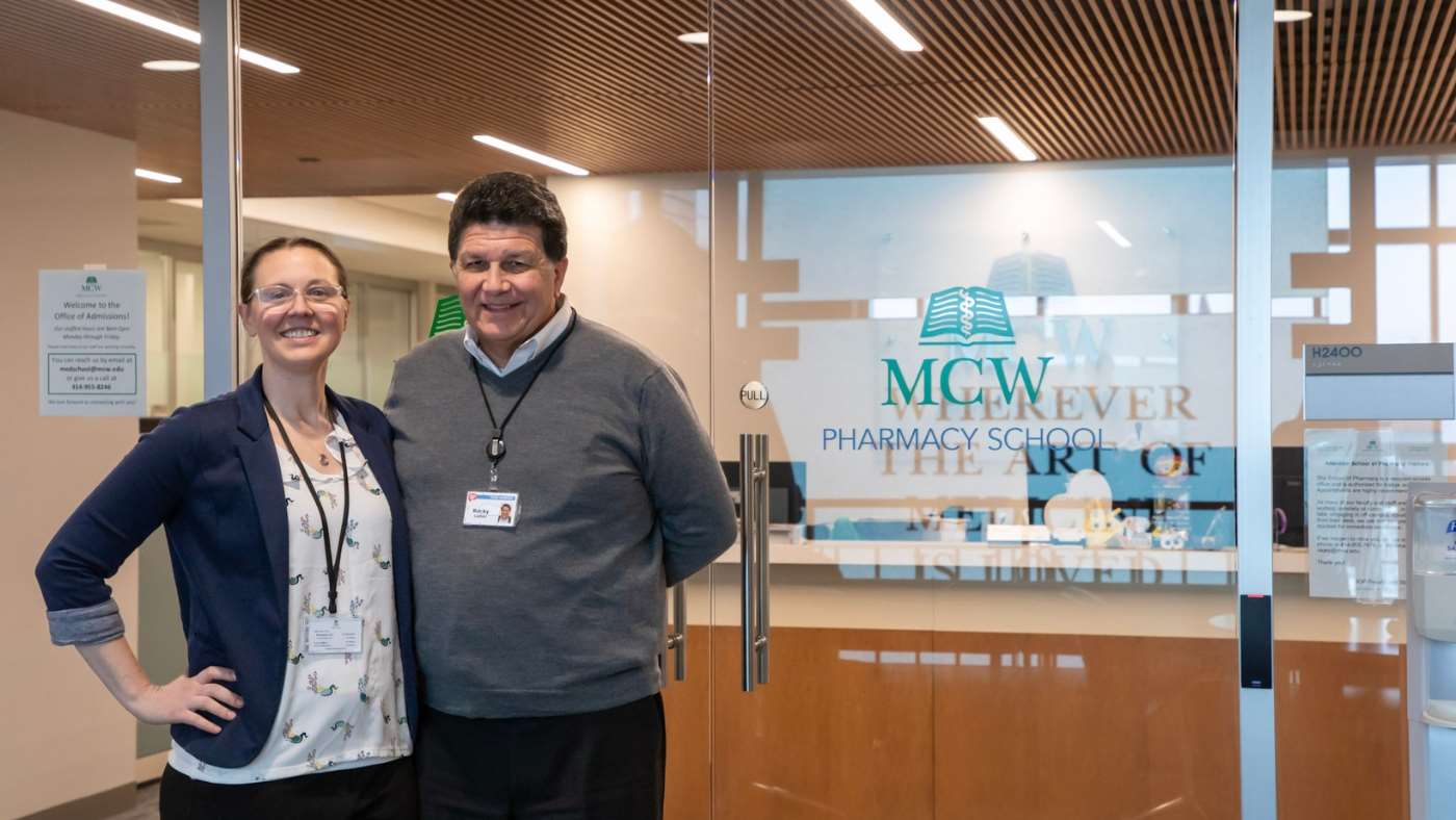 A woman and a man standing in front of a glass office door