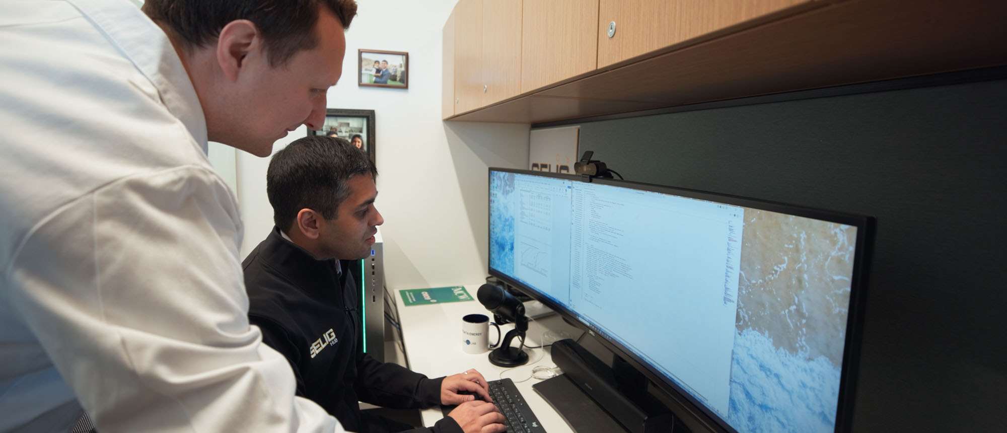 Two men reviewing information on computer screens