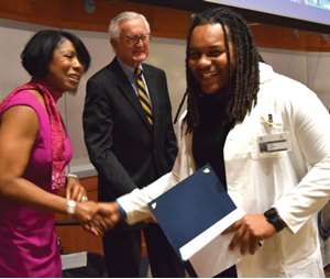 University of Wisconsin-Milwaukee senior Carl Greer receiving his graduation certificate from Dr. Doriel Ward and former MCW Trustee Chas Mulcahy