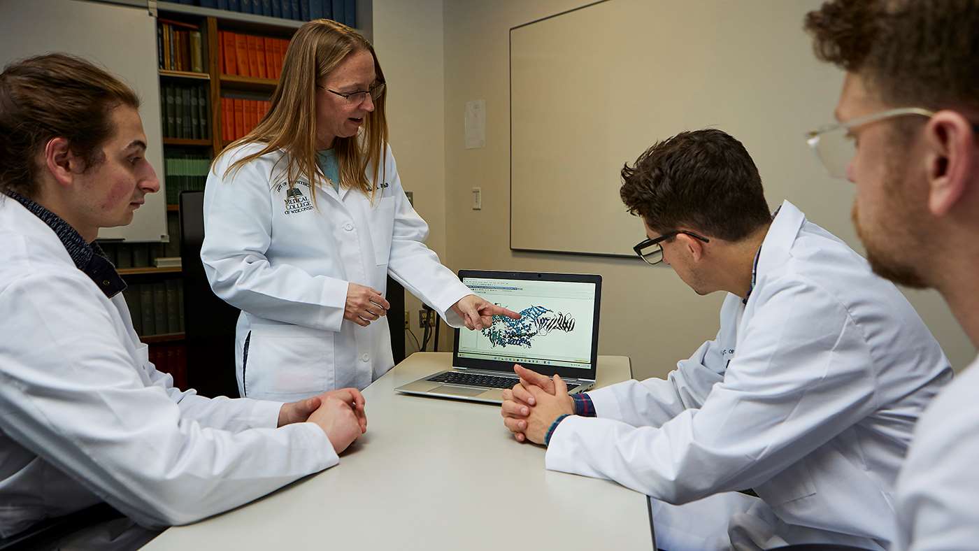 MCW researcher Dr. Candice Klug and three male colleagues meeting in conference room