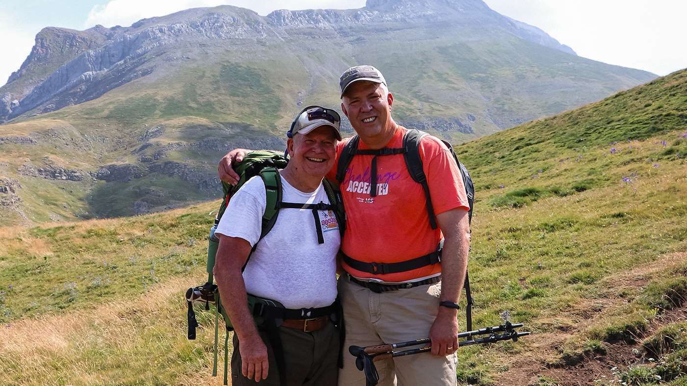 Two men standing in front of a mountain