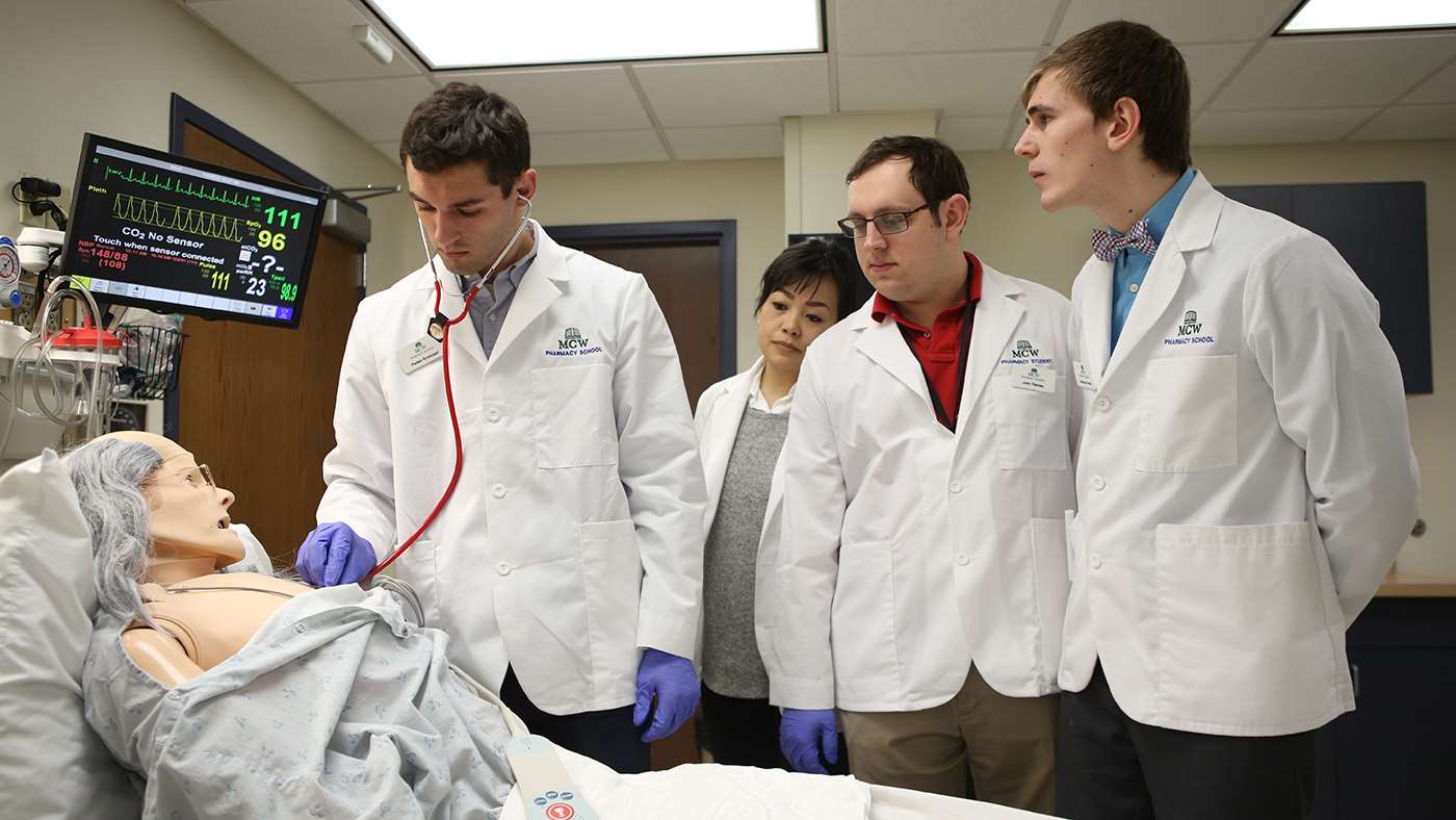 Dr. Parker Knueppel (top left and below) checks the heartbeat of a simulation mannequin