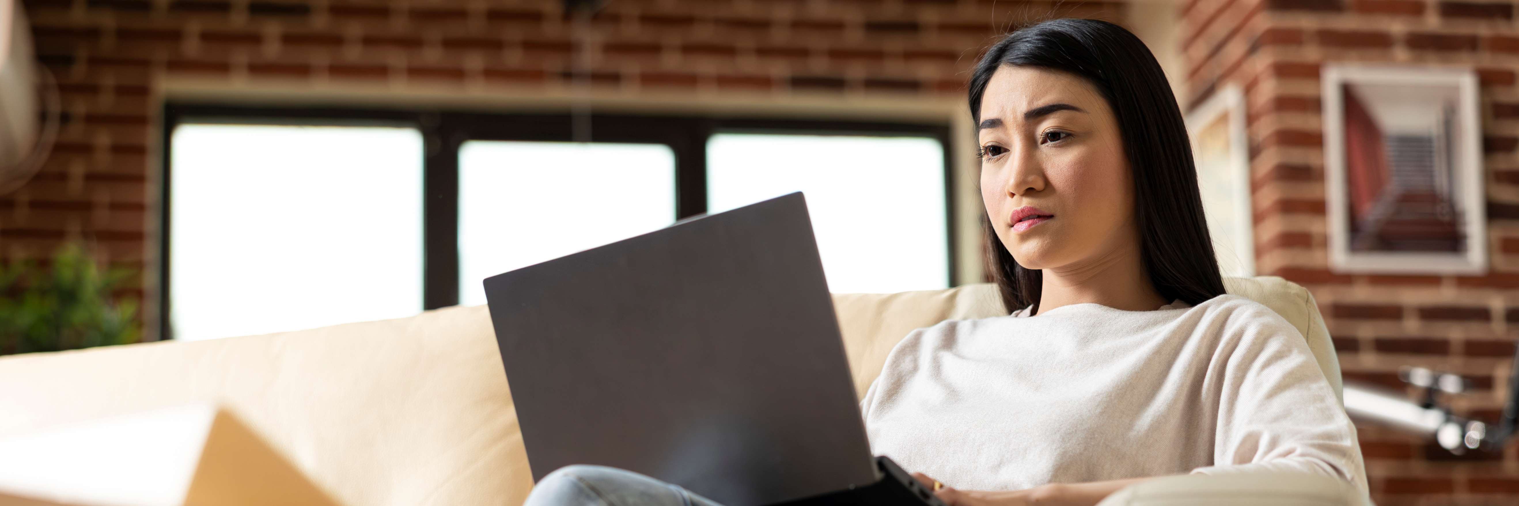Woman on couch working at laptop