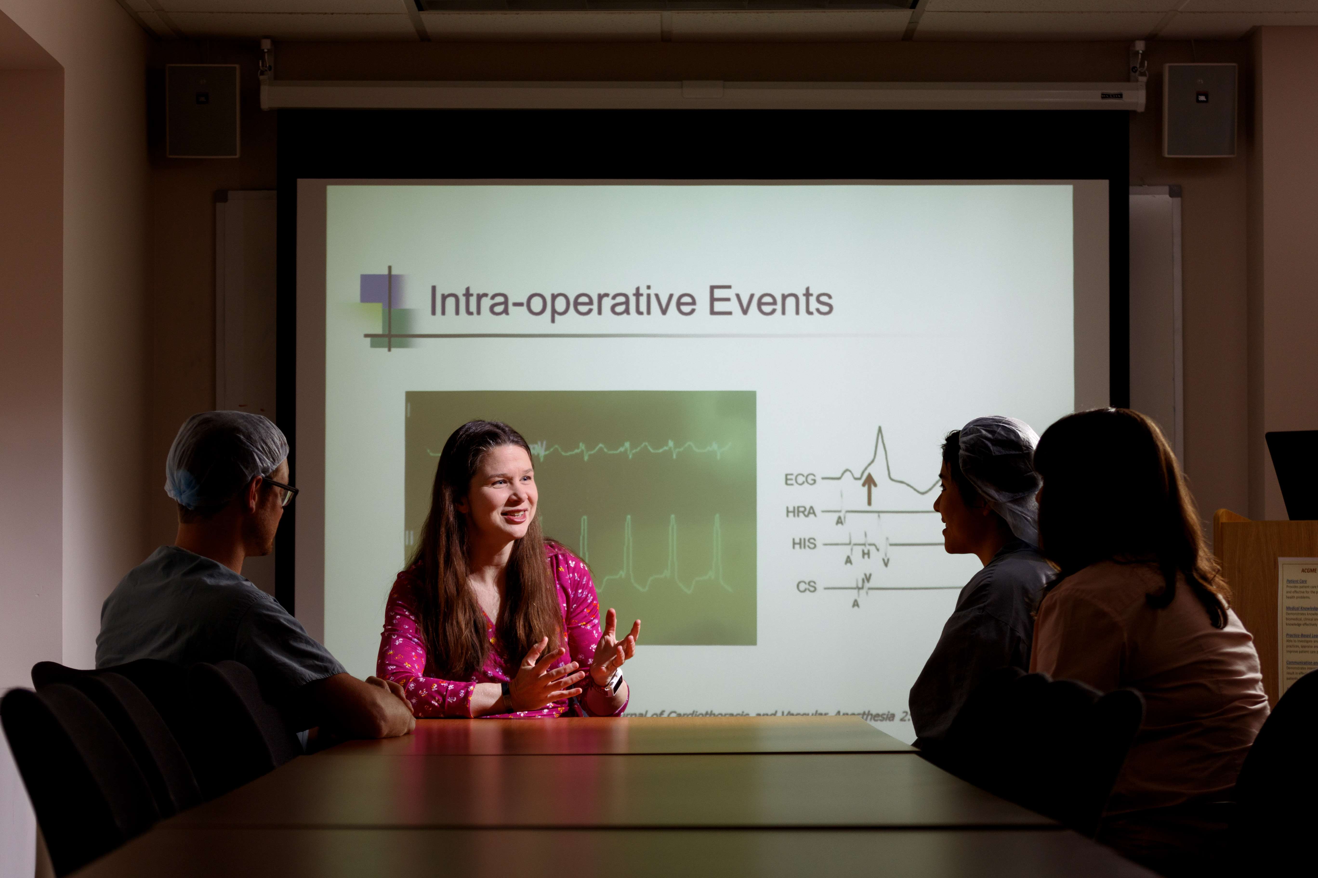 Two educators and two trainees having a discussion with a slide presentation in the background