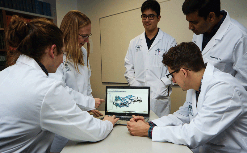 professor and students gathered around a computer