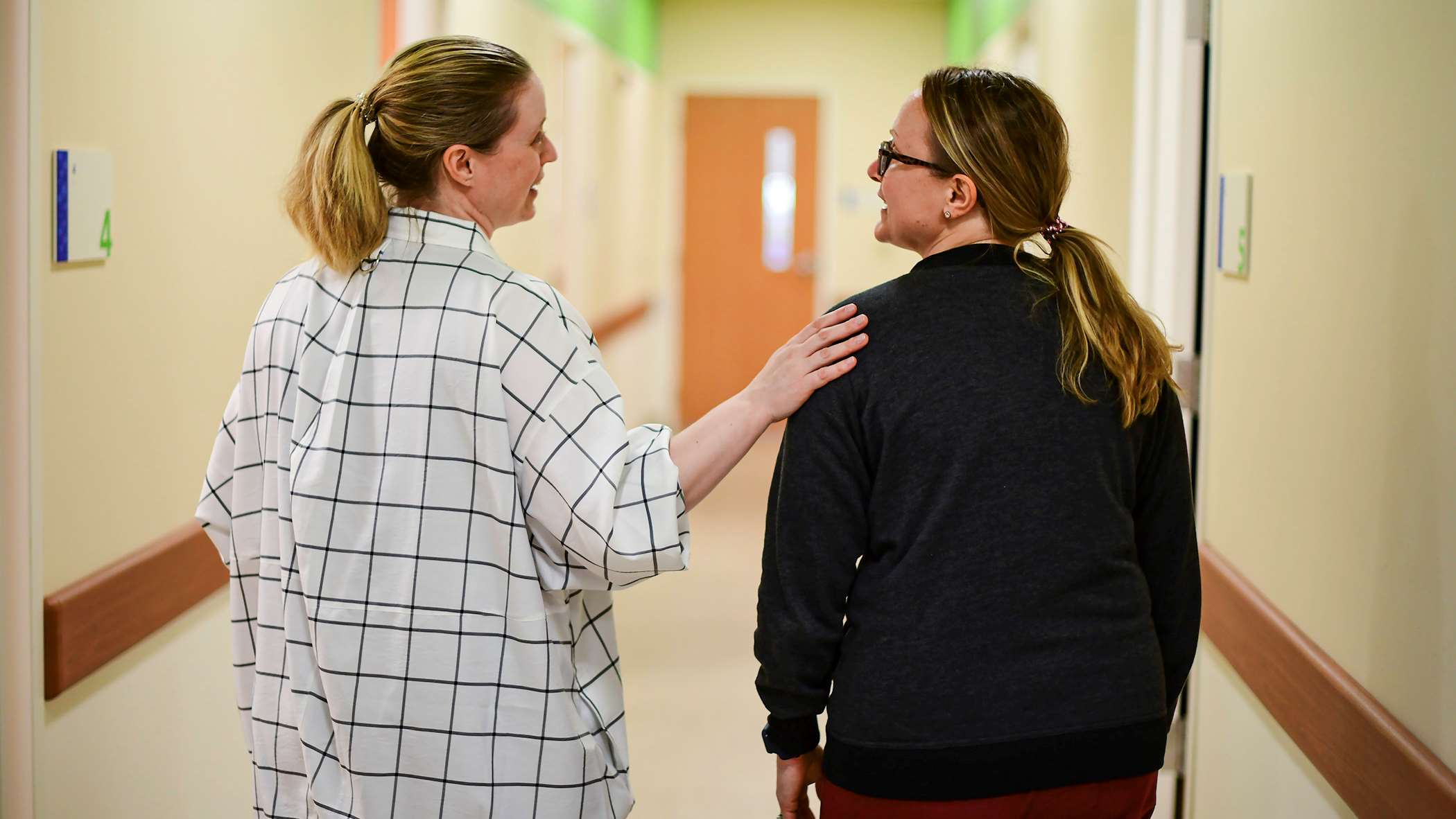 Two women walking down a hallway