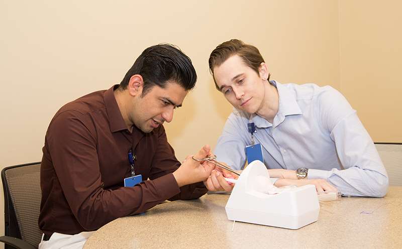 Two men practicing suturing