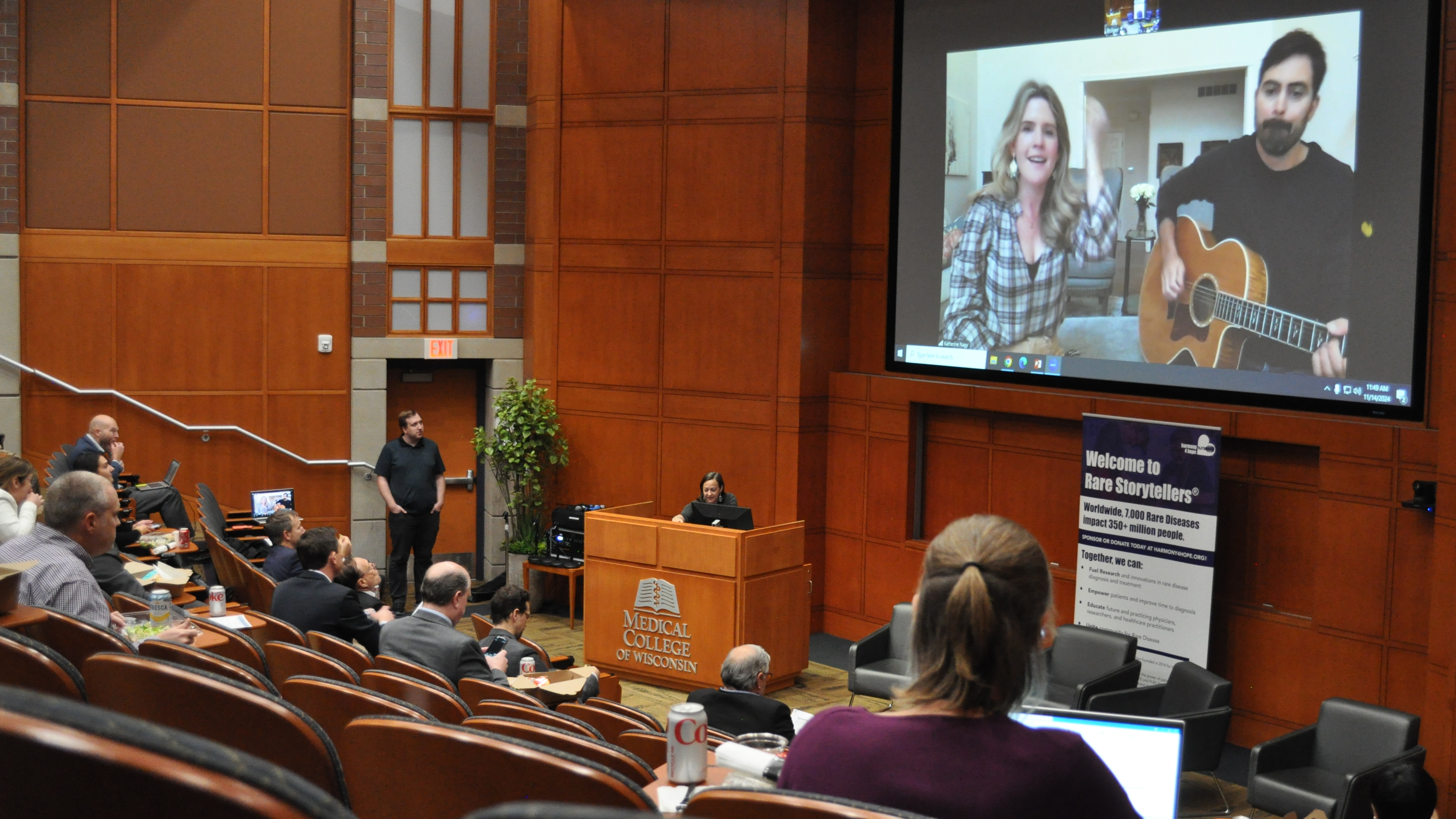 Harmony4Hope Rare Storytellers musicians on big screen at front of auditorium.