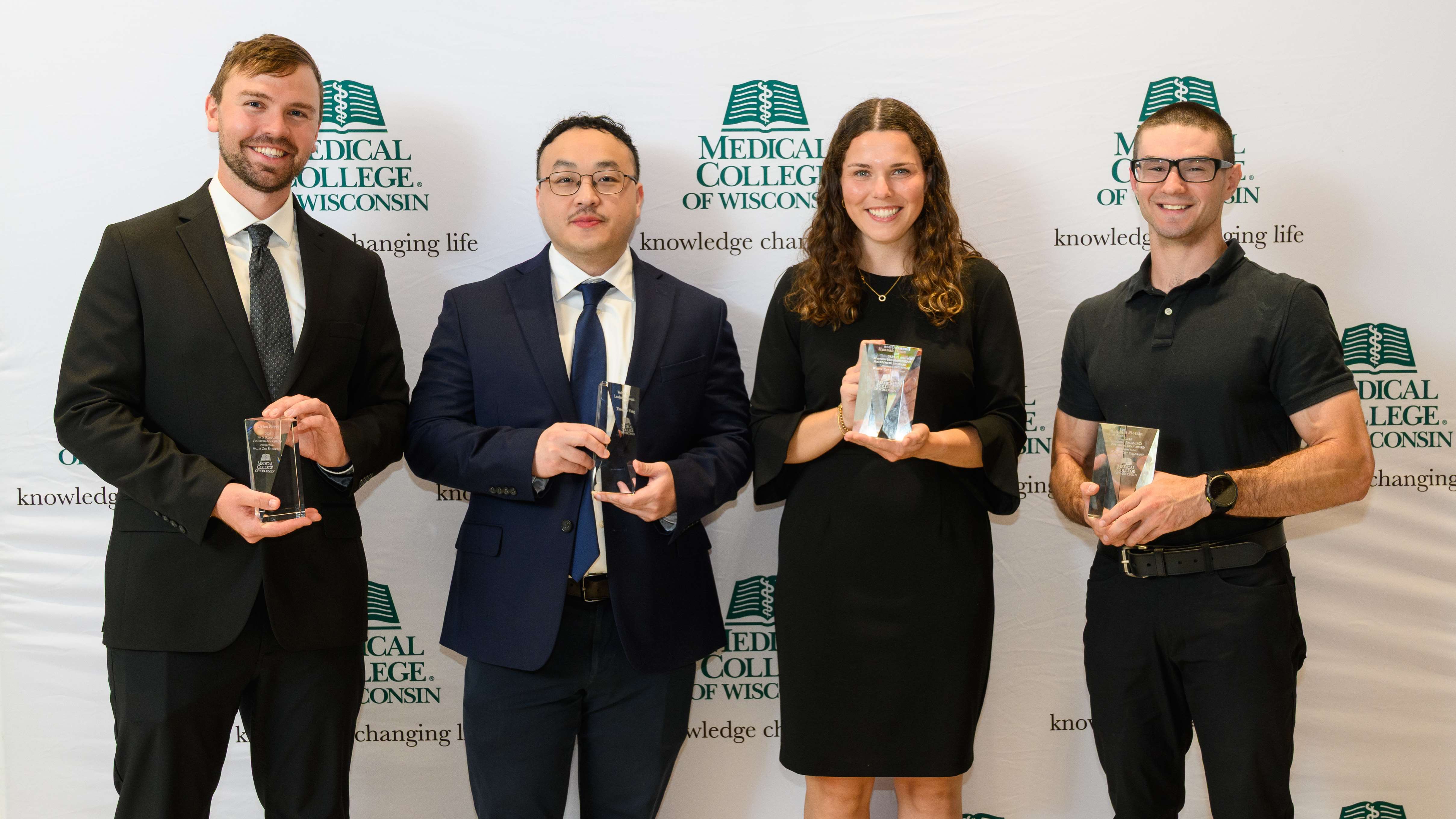 Three men and one woman holding awards