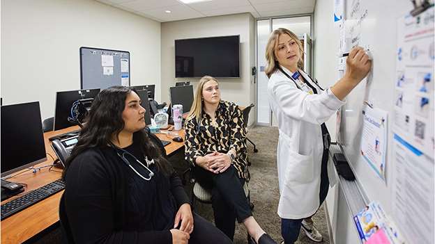 Three doctors in scrubs walking in hospital hallway