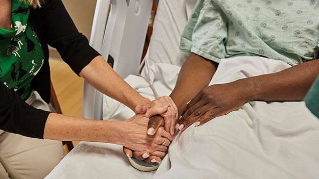 A woman holding a female patient's hands