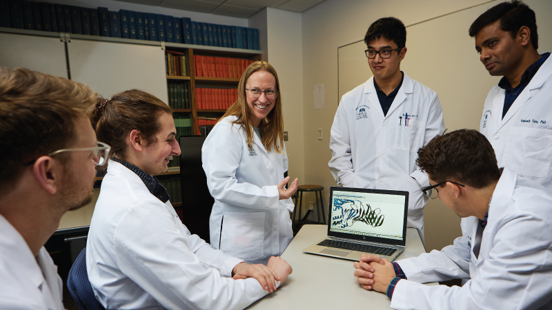 a professor and students gathered around a computer
