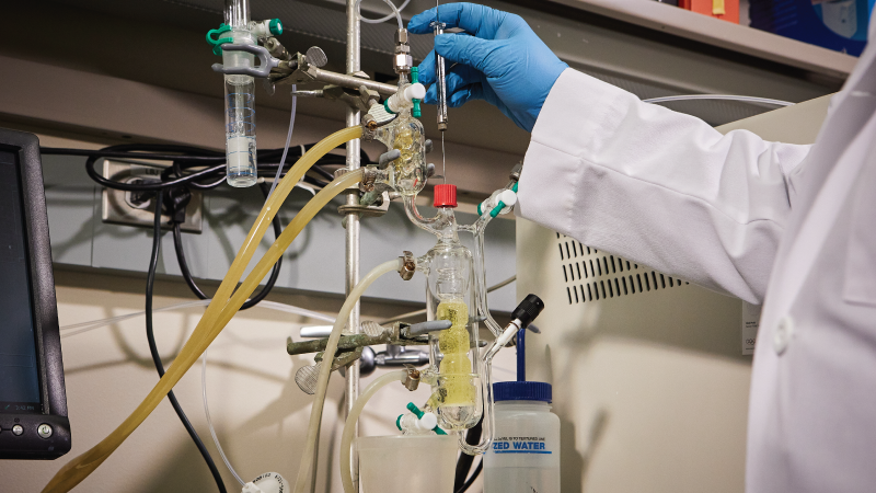 a closeup of a gloved hand performing an experiment