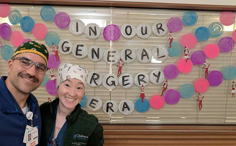 Two people standing in front of a decorated window