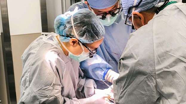 Three surgeons operating on a patient in an operating room