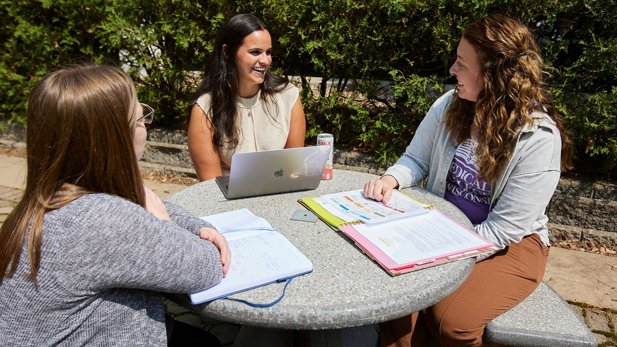 Three women sitting in campus courtyard