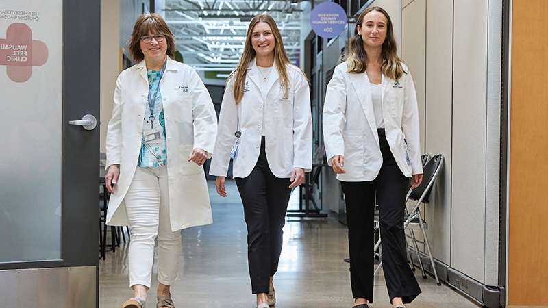A doctor and two medical students walking down a hallway