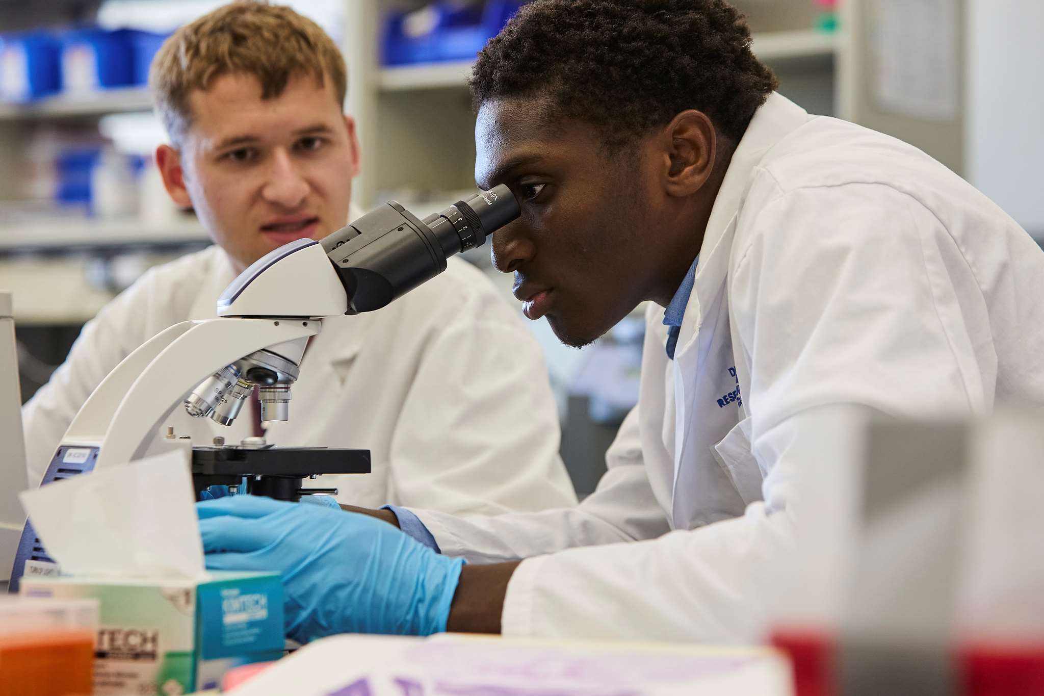 Two students looking through microscope