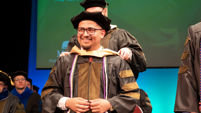 Alberto Aranda_Testimonial Alberto Aranda, PharmD, in graduation robes and cap at the MCW School of Pharmacy Hooding Ceremony in 2023.