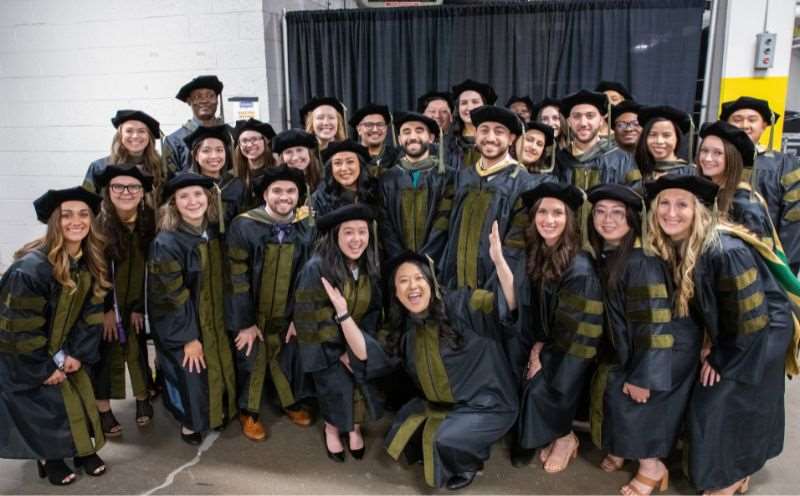 A group of pharmacy students in their caps and gowns pose for a photo at the Commencement ceremony