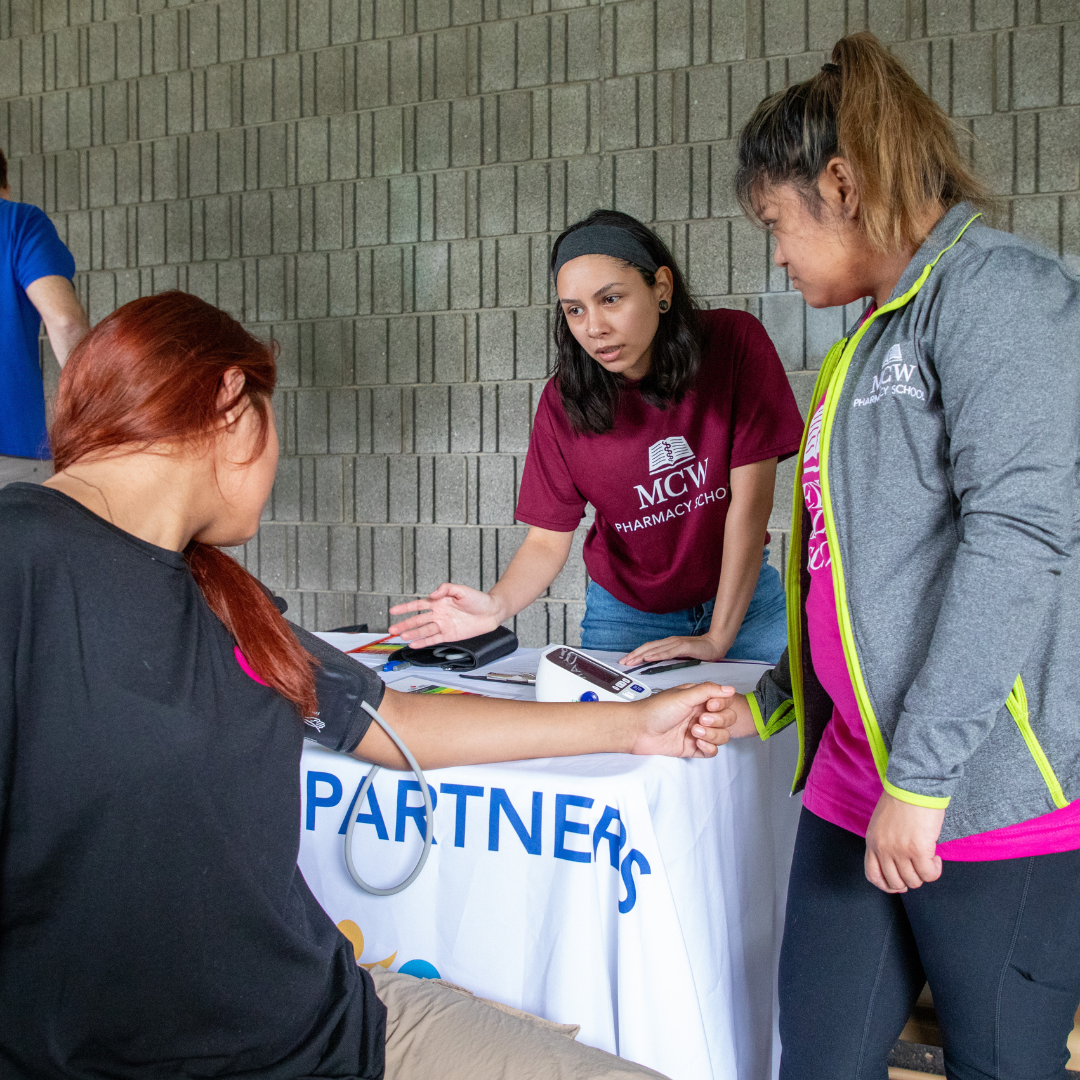 Engage Two pharmacy students talk with a community member who is having her blood pressure taken.