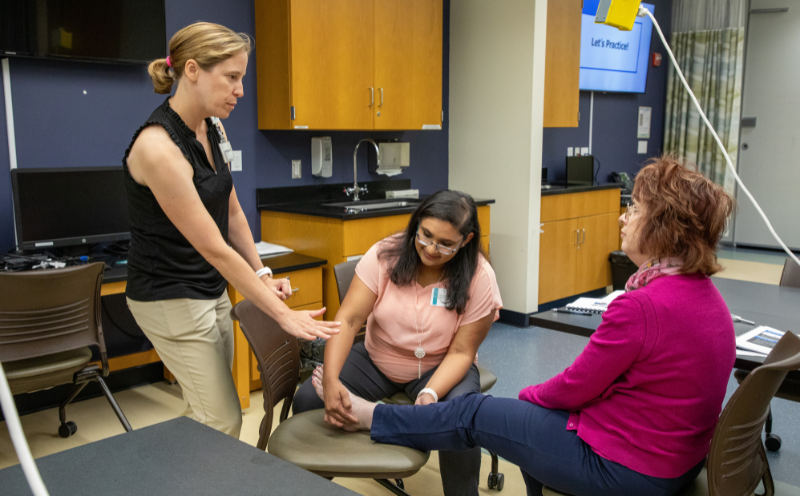 Professor explains to two students how to perform a diabetic foot exam.