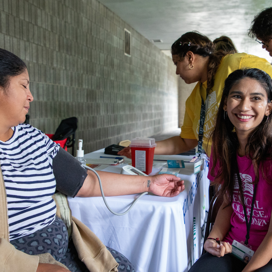 Pharmacy Student takes a woman's blood pressure at a community event.