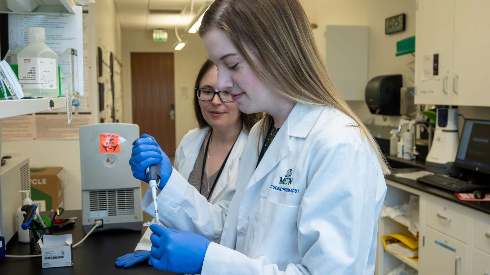 Pharmacy student works in a laboratory setting alongside her preceptor.