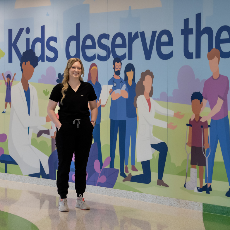 Rachael Jaszczenski_Alumni Quote Rachael Jaszczenski, PharmD, alumna of the MCW School of Pharmacy, stands in front of a mural at Children's Wisconsin.