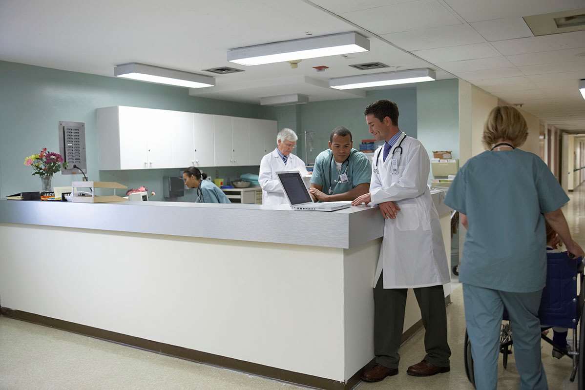 Physicians collaborate around counter in clinic