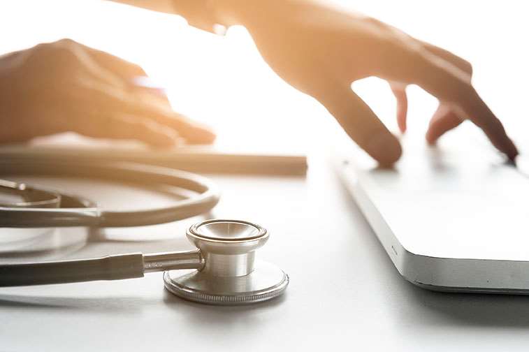 Hand with halo effect on keyboard with stethoscope