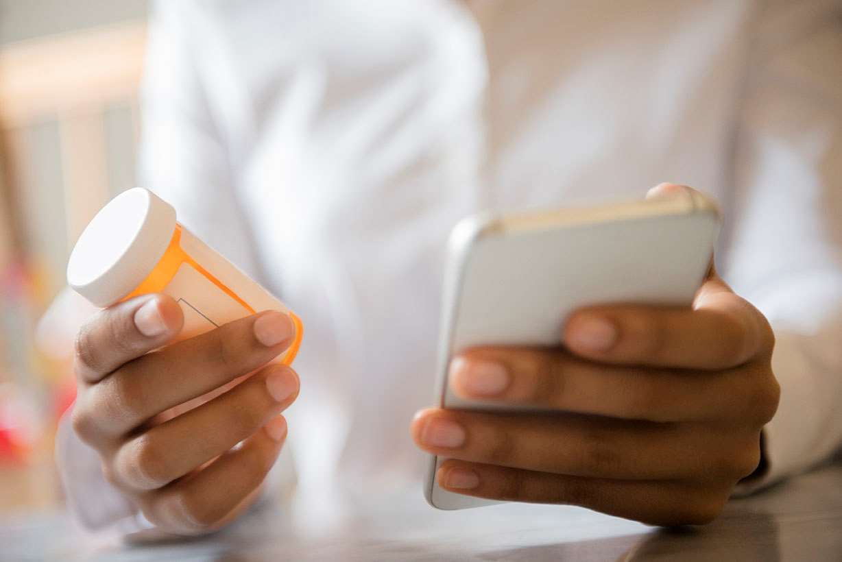 Hands with mobile device and prescription bottle
