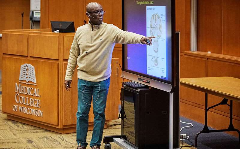 faculty lecturing and pointing to a television screen