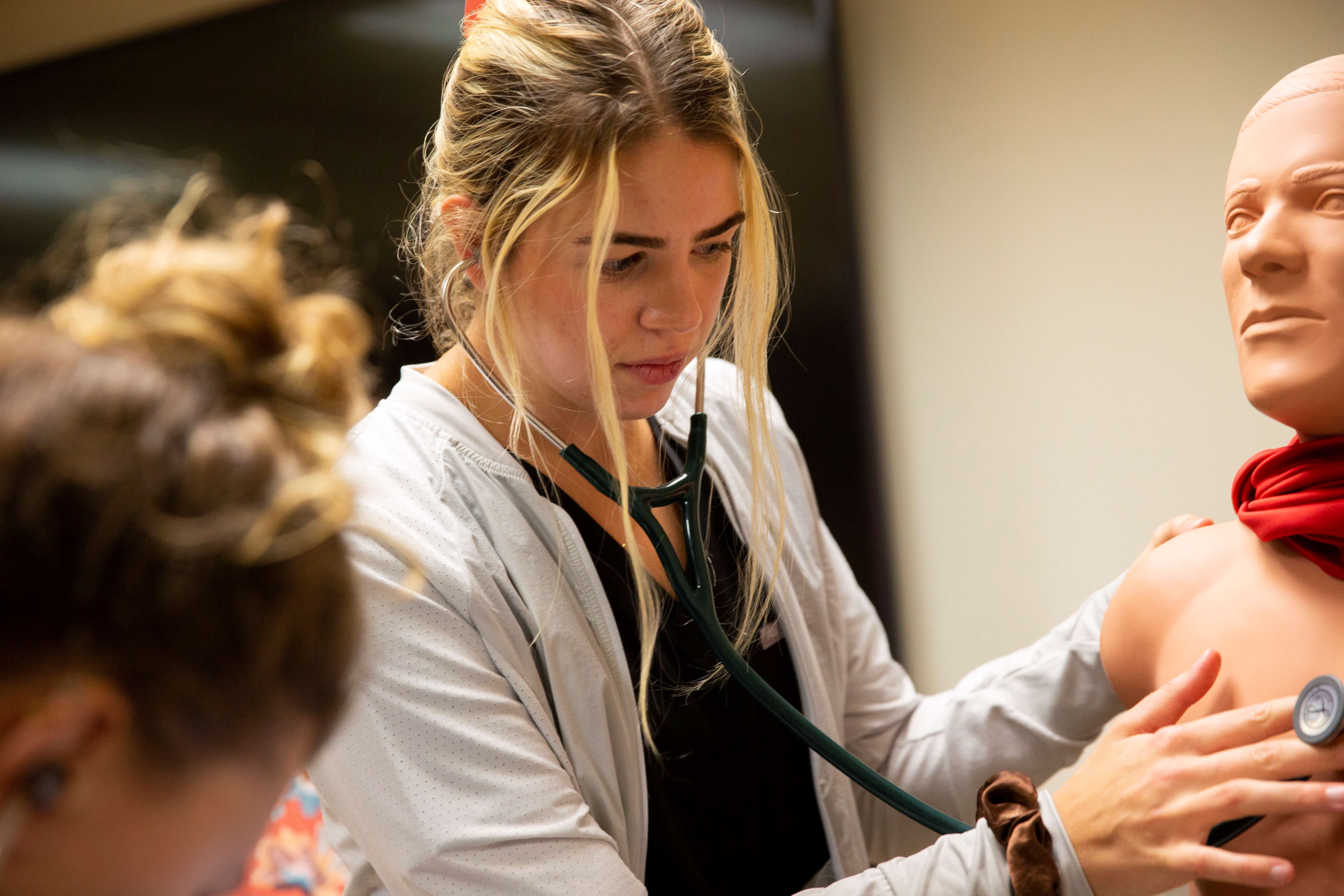 medical student using stethoscope on mannequin
