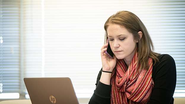 Woman talking on phone in front of laptop
