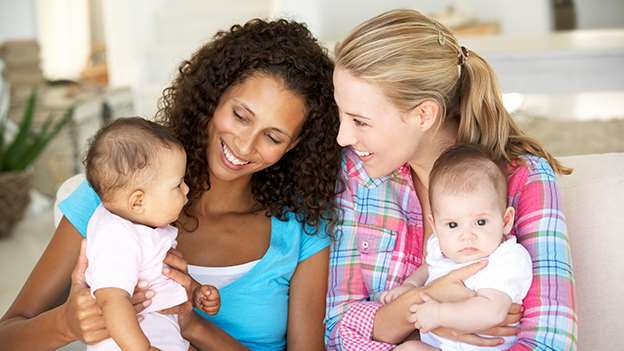 Two women each holding a baby