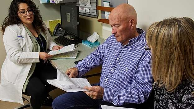 A doctor talking with a male patient and female partner