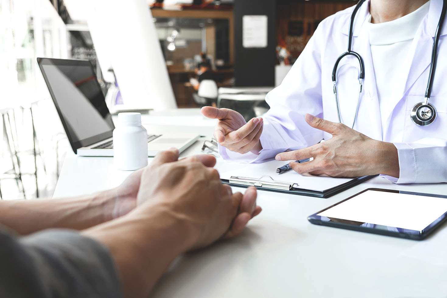 Physician and patient hands desk discussion